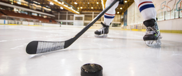 hockey player with stick and puck on ice