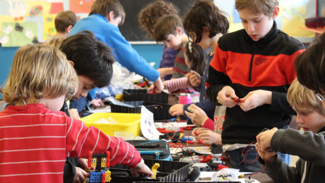 Children engaged in a group crafting activity in a classroom setting.