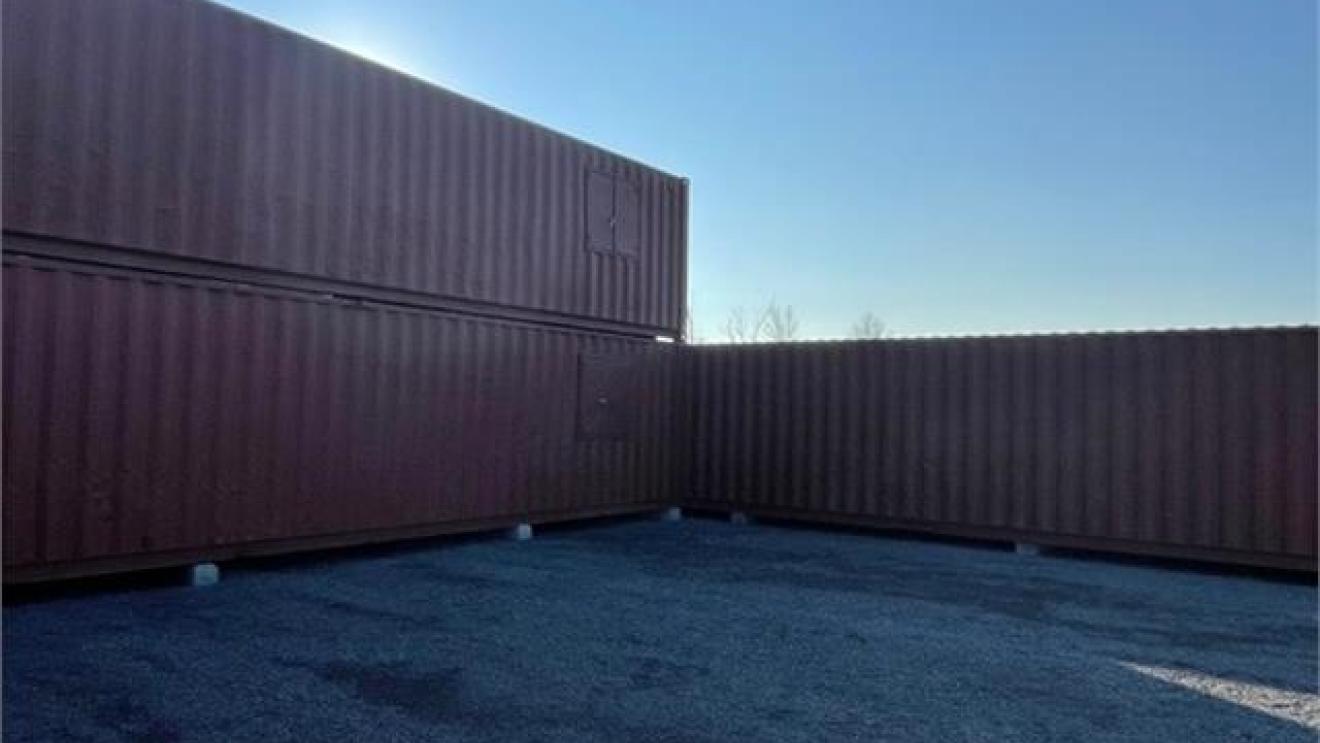 Shipping containers stacked outdoors under a clear blue sky.