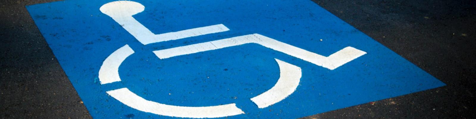 Accessible parking symbol painted on a blue background.