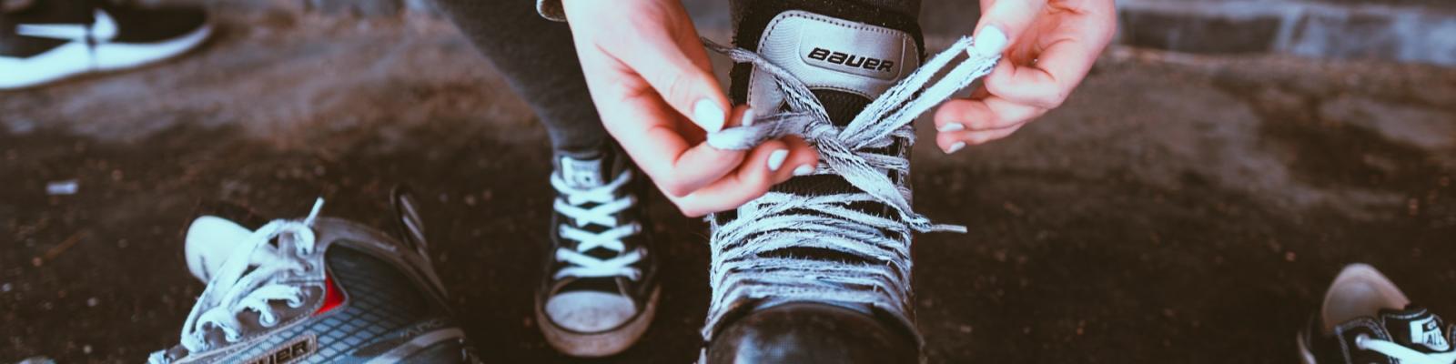 Tying skate laces on roller skates in a dimly lit area.