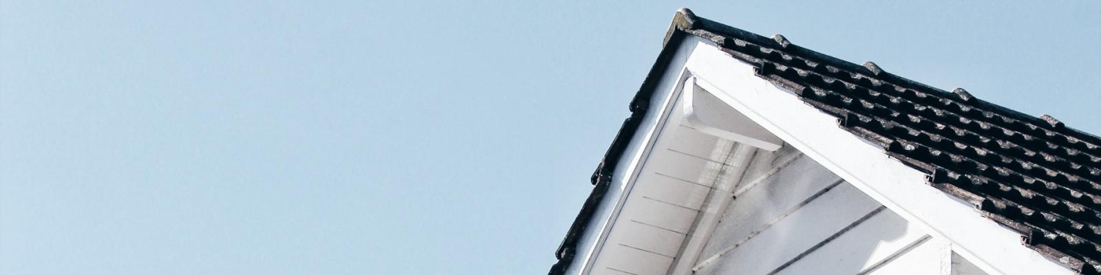 White gable roof with dark shingles against clear blue sky.